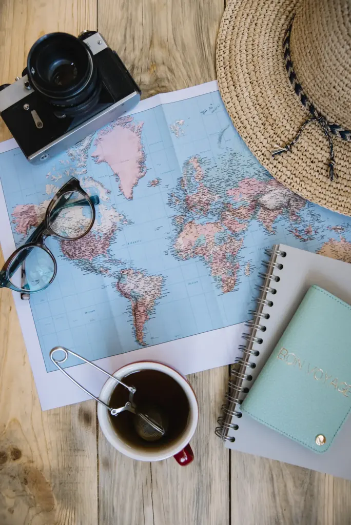 Lifestyle Creep Doesn't End at Retirement 1 World map on a wooden table with a camera, sun hat, eyeglasses, a cup of tea and a notebook